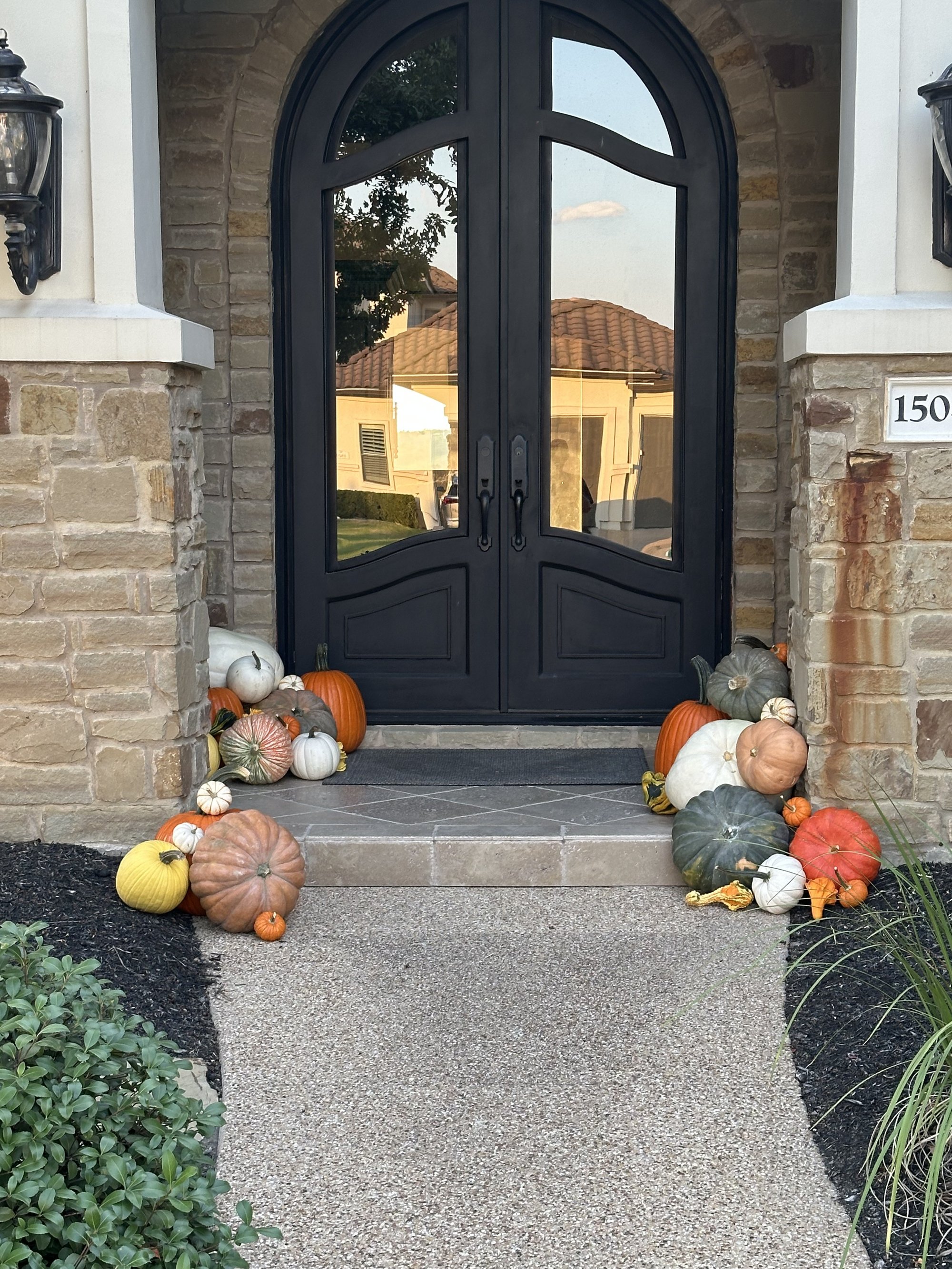 Pumpkin displays framing arched iron doors at a stone Austin home