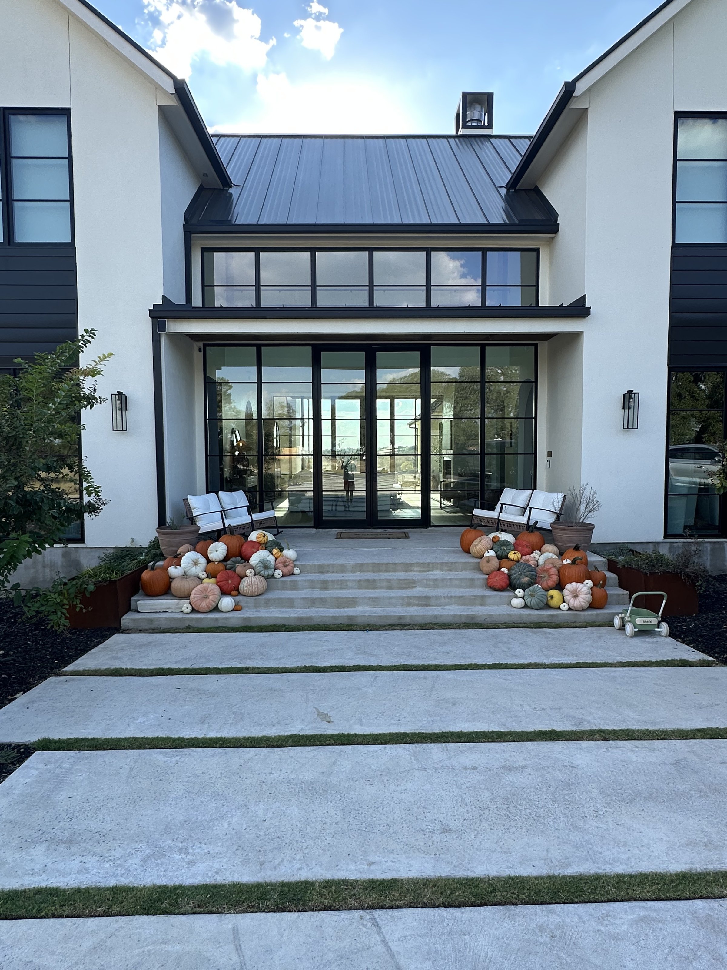 Twin pumpkin and hay bale displays styled by Longhorn Pumpkins flanking the entry of a modern Austin home
