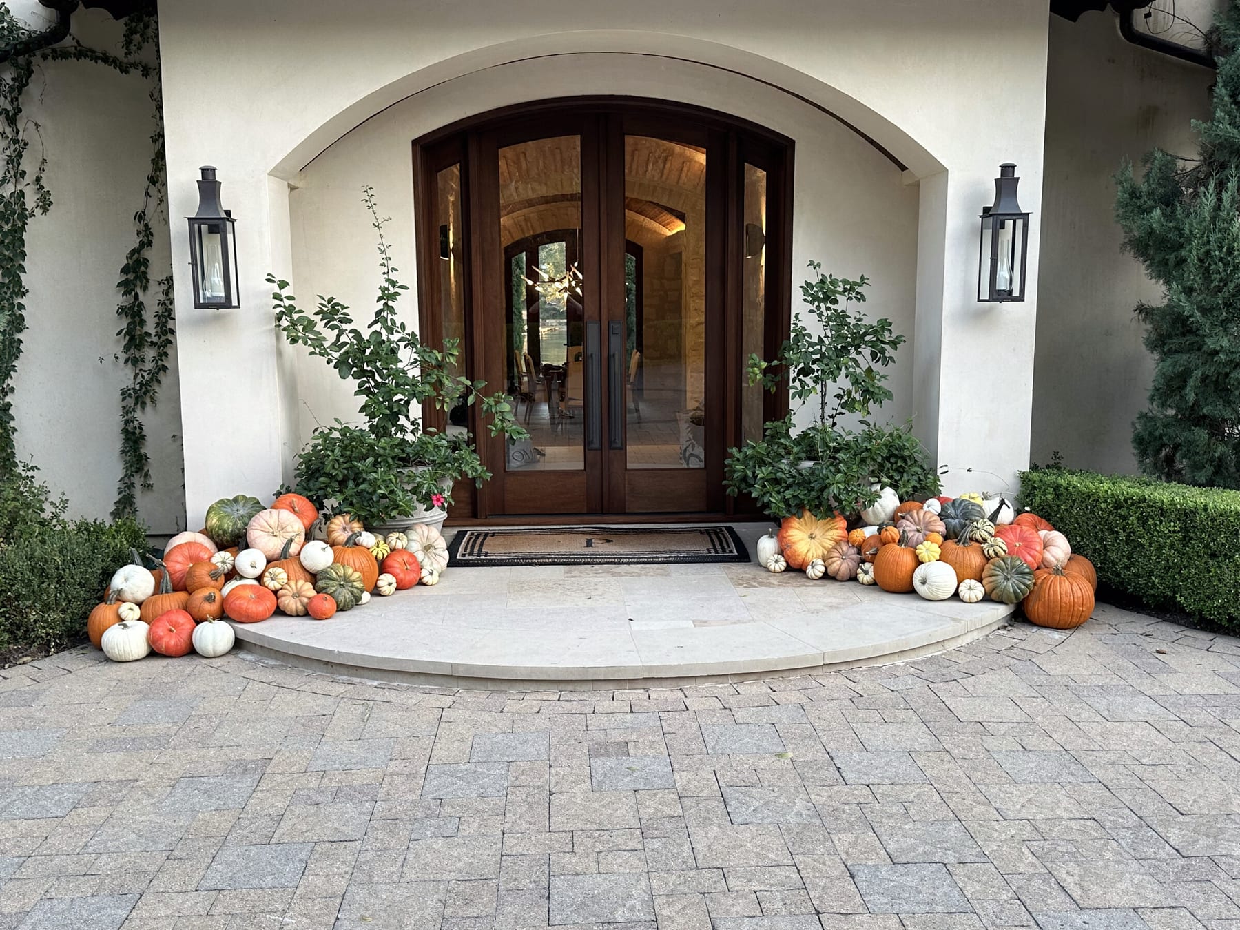 The Longhorn Grand installed at a front entry — pumpkins and gourds flanking a curved limestone step at the arched wood doors of a stucco home