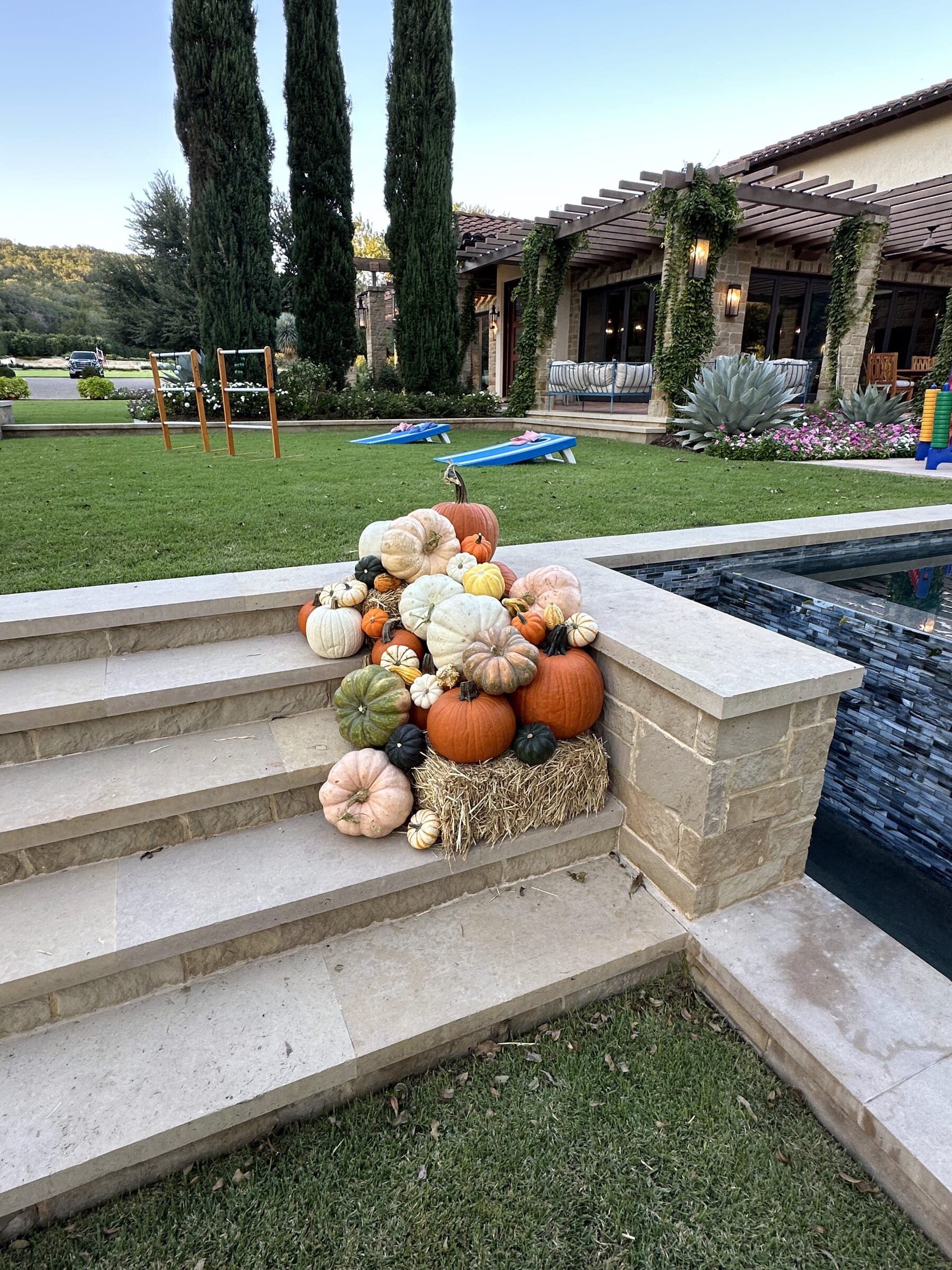 More of the same Longhorn Grand order — a stacked arrangement on a hay bale beside limestone pool steps, cypress trees behind